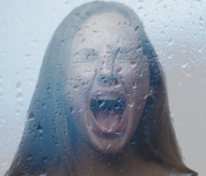 Woman screaming behind glass with water on it